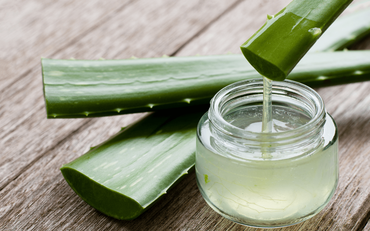 Čerstvá aloe vera vytékající z listu do skleněné nádoby na dřevěném povrchu